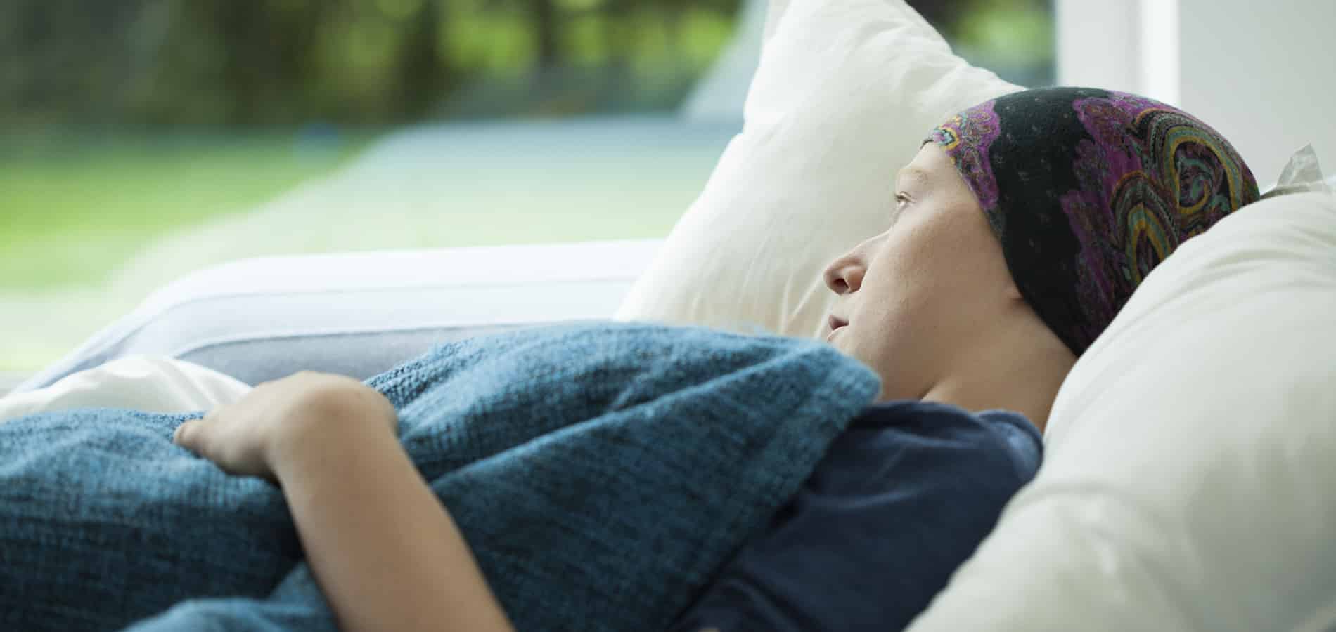 Syöpää sairastva nainen makaa sängyssä.