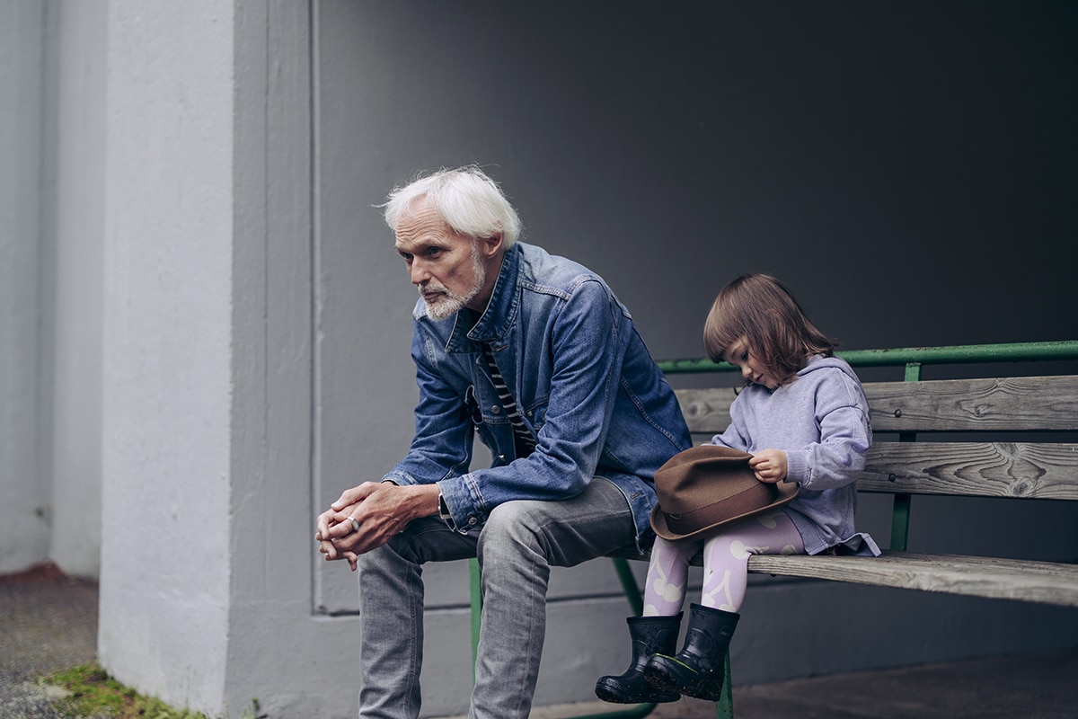 Iäkäs mies ja pieni lapsi istuvat penkillä.